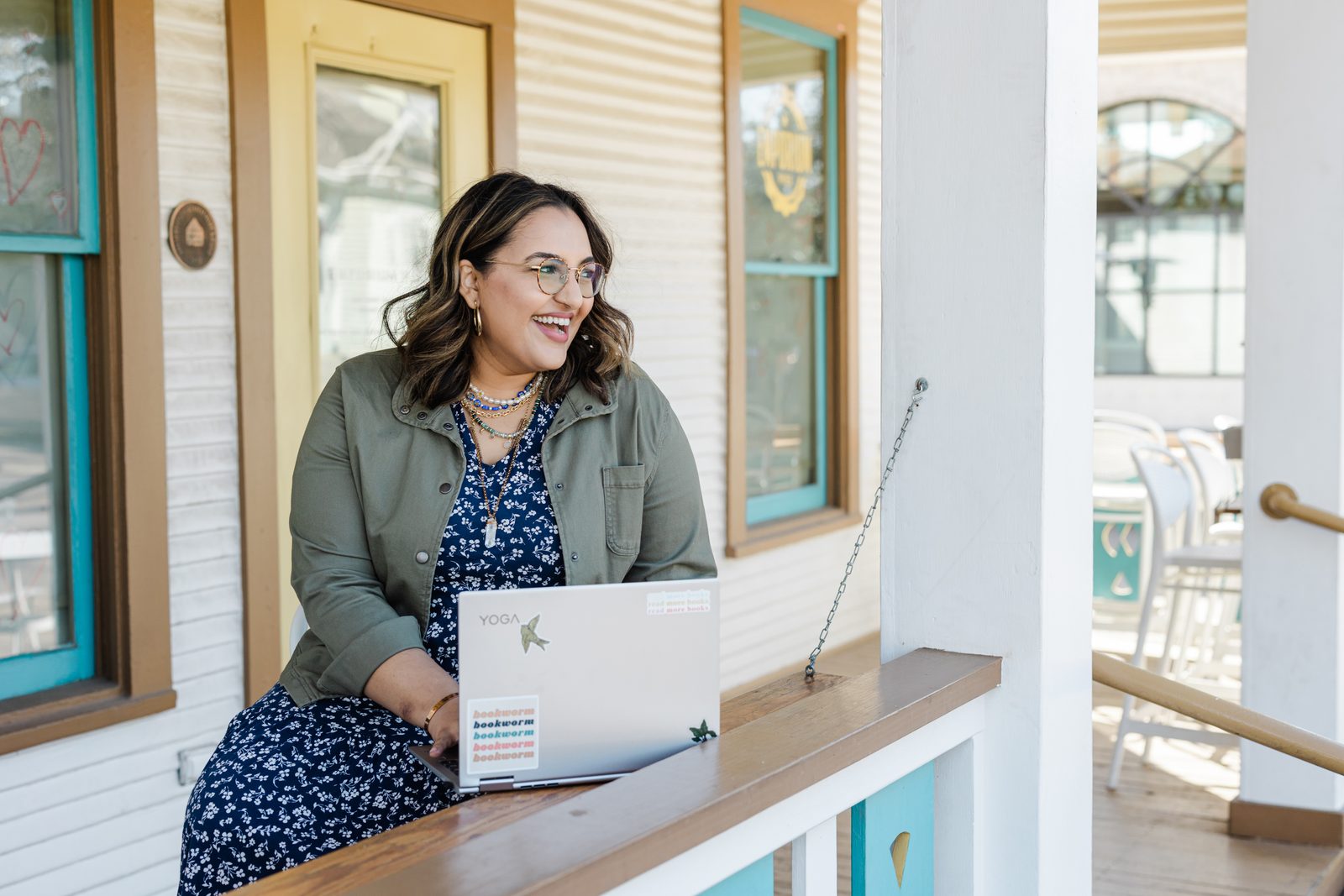 Ashmi laughing while working on her laptop on a sunny porch